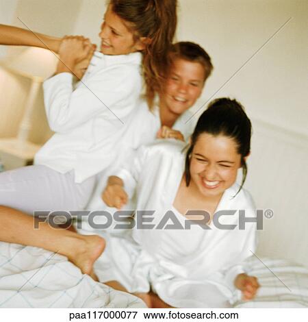 Young people playfighting on bed, smiling View Large Photo Image Stock Photo - Young people playfighting on bed, smiling. Fotosearch