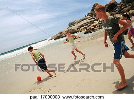 Stock Image - Young people playing soccer at the beach. Fotosearch
