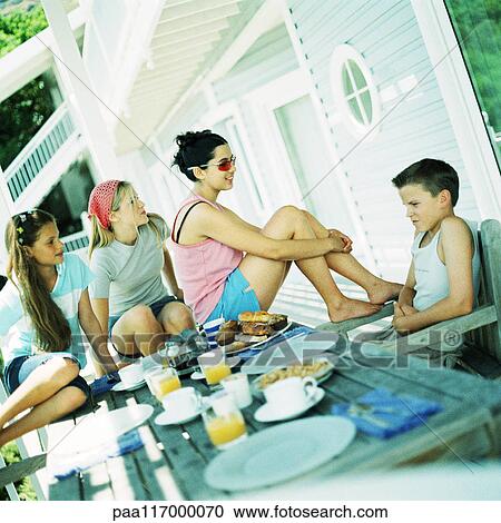 Young people sitting around table, outside View Large Photo Image Stock Image - Young people sitting around table, outside. Fotosearch
