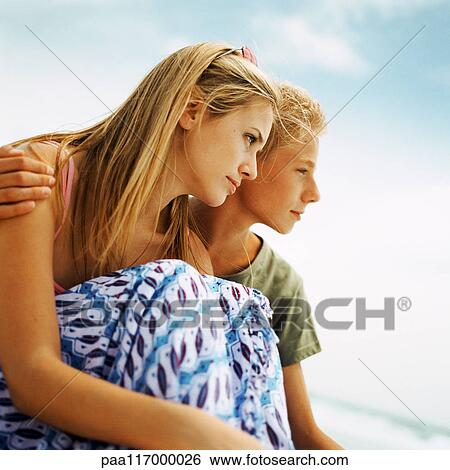 Young people sitting side by side outside, side view View Large Photo Image Stock Photograph - Young people sitting side by side outside, side view. Fotosearch