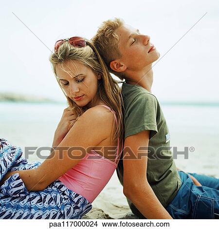 Young woman and boy sitting on the sand back to back View Large Photo Image Picture - Young woman and boy sitting on the sand back to back. Fotosearch
