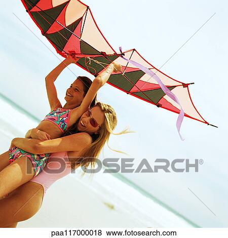 Young woman carrying girl with kite on the beach View Large Photo Image Stock Photo - Young woman carrying girl with kite on the beach. Fotosearch