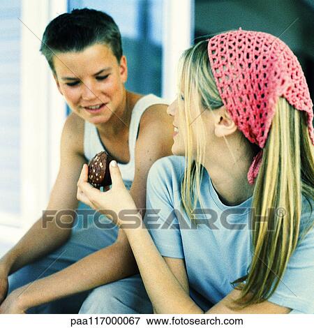 Young woman handing brownie to teenage boy View Large Photo Image Stock Photo - Young woman handing brownie to teenage boy. Fotosearch