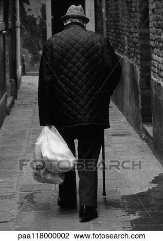 Man walking with cane, holding grocery bags, rear view, b&w View Large Photo Image Stock Image - Man walking with cane, holding grocery bags, rear view, b&w. Fotosearch