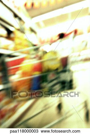 Stock Image - Shopping cart in grocery store, blurred. Fotosearch