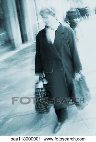 Woman carrying shopping bags, blurred View Large Photo Image Stock Image - Woman carrying shopping bags, blurred. Fotosearch
