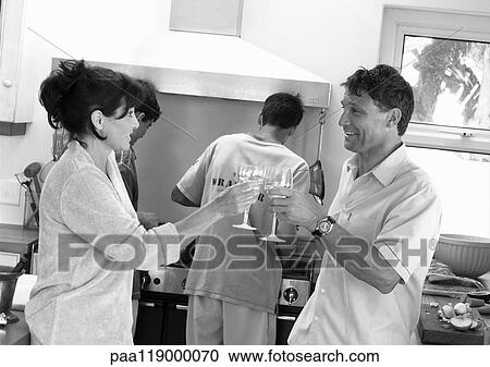 Couple clinking glasses in kitchen, teeange boys cooking, b&w View Large Photo Image Stock Image - Couple clinking glasses in kitchen, teeange boys cooking, b&w. Fotosearch