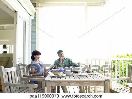 Couple sitting at table, outside View Large Photo Image Stock Image - Couple sitting at table, outside. Fotosearch