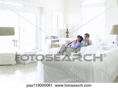 Couple sitting on sofa View Large Photo Image Stock Image - Couple sitting on sofa. Fotosearch