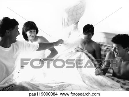 Picture - Family having pillow fight in bed, b&w. Fotosearch