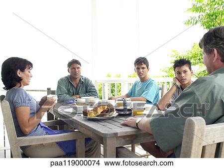 Picture - Family sitting at table, outside. Fotosearch