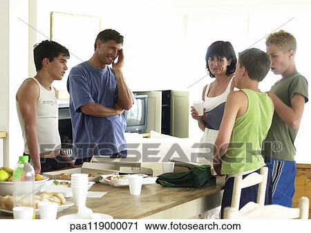 Stock Image - Family standing around table. Fotosearch