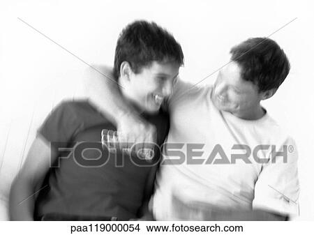 Father sitting with arm around teenage boy's neck, blurred, b&w View Large Photo Image Picture - Father sitting with arm around teenage boy's neck, blurred, b&w. Fotosearch