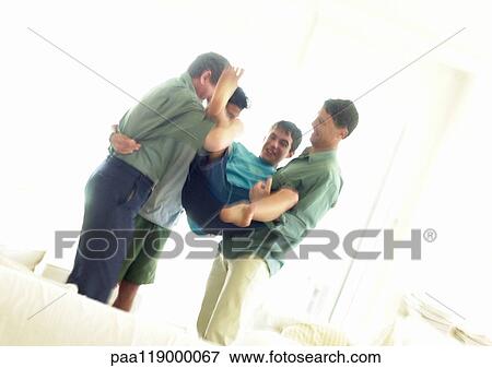 Grandfather, father and boys standing in living room, playfighting View Large Photo Image Stock Photo - Grandfather, father and boys standing in living room, playfighting. Fotosearch