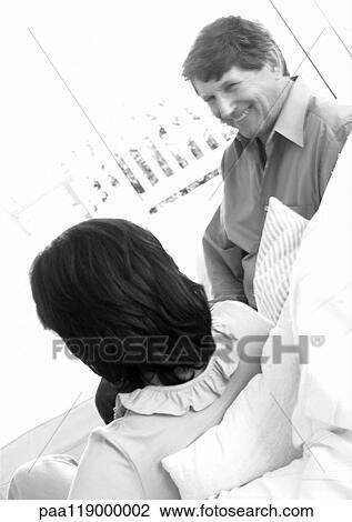 Stock Image - Mature couple sitting on sofa, b&w. Fotosearch
