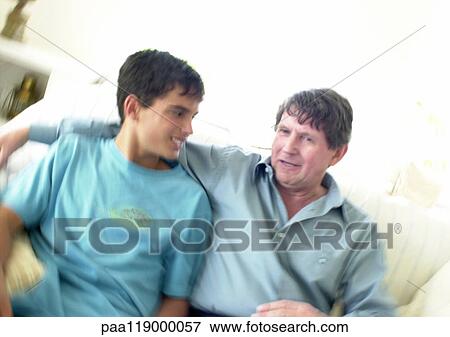 Teenage boy and mature man sitting on sofa, blurred View Large Photo Image Stock Photo - Teenage boy and mature man sitting on sofa, blurred. Fotosearch