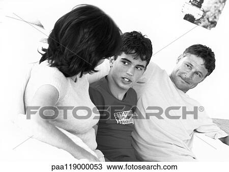 Stock Image - Teenage boy sitting between parents, b&w. Fotosearch