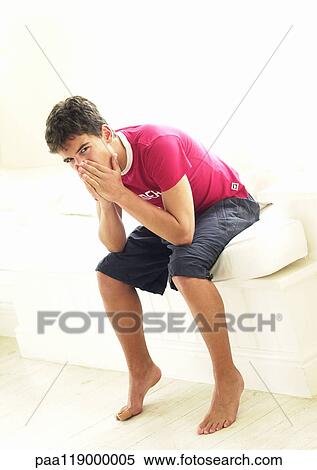 Stock Photography - Teenage boy sitting, hands on face. Fotosearch
