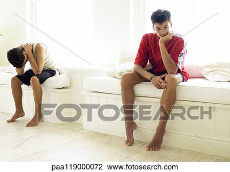 Stock Image - Two teenage boys sitting apart. Fotosearch