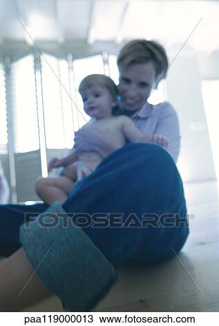 Woman holding baby, low angle view View Large Photo Image Stock Image - Woman holding baby, low angle view. Fotosearch