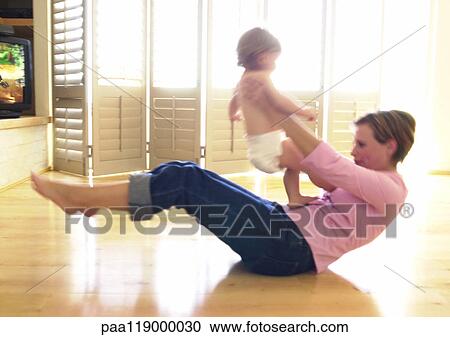 Stock Image - Woman on floor, holding baby. Fotosearch