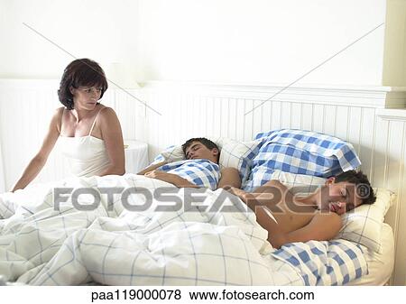 Woman sitting on edge of bed, looking at teenage boys sleeping View Large Photo Image Stock Photo - Woman sitting on edge of bed, looking at teenage boys sleeping. Fotosearch