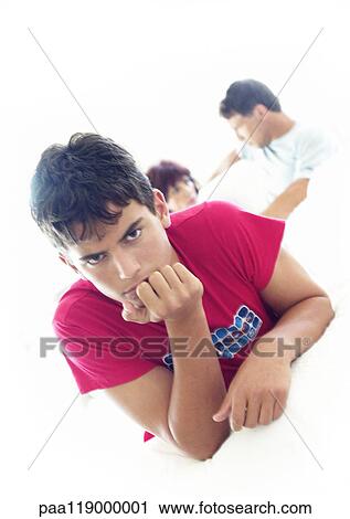 Young man with hand under chin, parents talking in background View Large Photo Image Stock Image - Young man with hand under chin, parents talking in background. Fotosearch