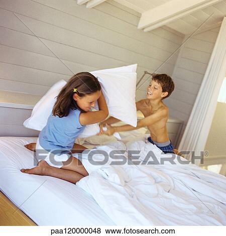 Stock Photo - Children having pillow fight in bed. Fotosearch