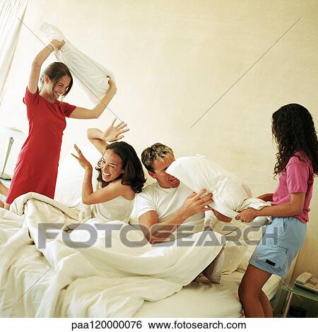 Family having pillow fight on bed View Large Photo Image Stock Photograph - Family having pillow fight on bed. Fotosearch