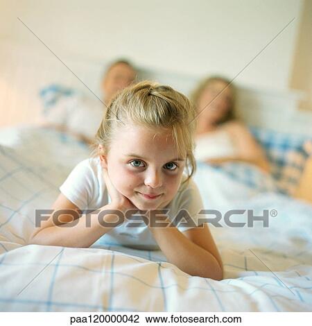 Girl lying at end of parent's bed View Large Photo Image Stock Image - Girl lying at end of parent's bed. Fotosearch