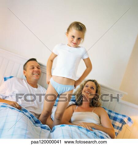 Girl standing between parents on bed View Large Photo Image Stock Image - Girl standing between parents on bed. Fotosearch