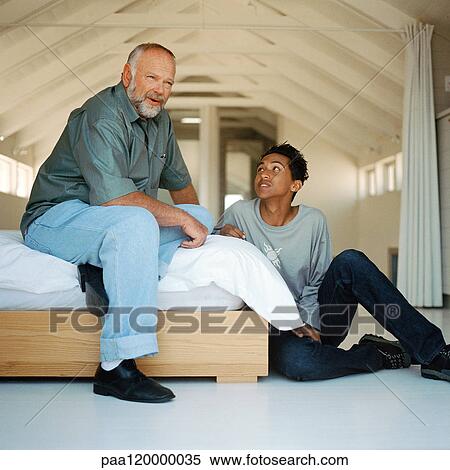 Mature man and teenage boy sitting and talking in bedroom View Large Photo Image Stock Photography - Mature man and teenage boy sitting and talking in bedroom. Fotosearch