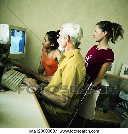 Stock Photo - Mature man and two girls using computer. Fotosearch