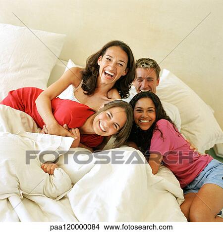 Picture - Parents and children on bed, smiling. Fotosearch