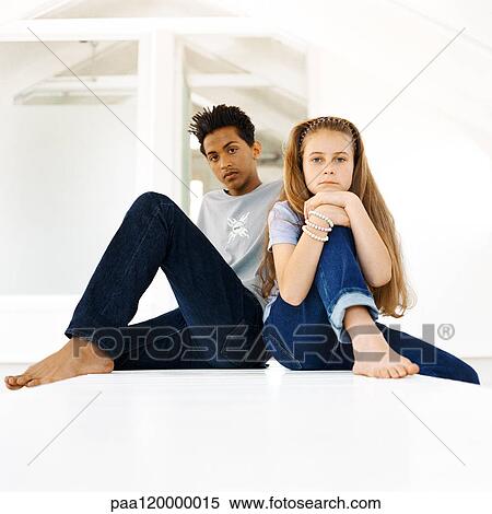 Teenage boy and girl sitting with knees up, looking into camera, portrait View Large Photo Image Stock Photography - Teenage boy and girl sitting with knees up, looking into camera, portrait. Fotosearch