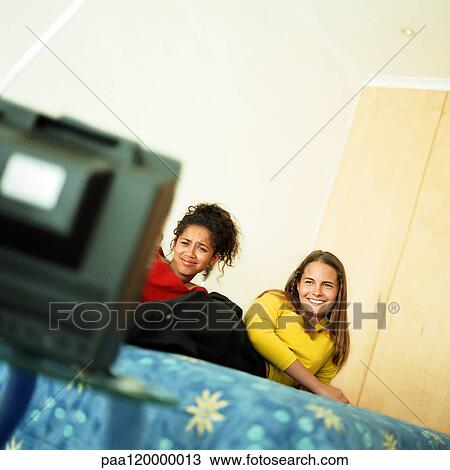 Two girls on bed watching television View Large Photo Image Stock Image - Two girls on bed watching television. Fotosearch