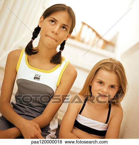 Stock Photo - Two girls sitting on stairs, portrait. Fotosearch