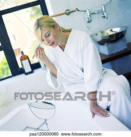 Woman applying make up in bathroom View Large Photo Image Stock Image - Woman applying make up in bathroom. Fotosearch