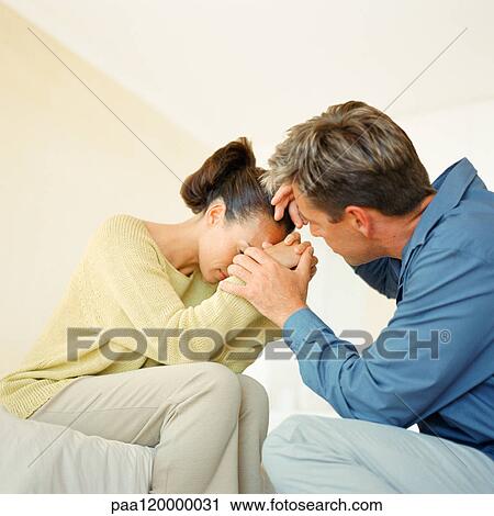 Woman sitting with hands in front of face, man holding woman's hands and stroking her head View Large Photo Image Stock Image - Woman sitting with hands in front of face, man holding woman's hands and stroking her head. Fotosearch