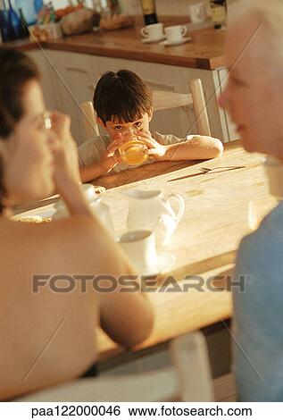 Child at table drinking from glass, with two women View Large Photo Image Stock Photograph - Child at table drinking from glass, with two women. Fotosearch