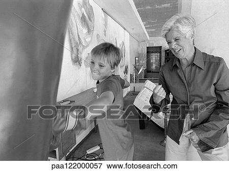 Child hitting punching bag, senior woman cheering him on, b&w View Large Photo Image Stock Photo - Child hitting punching bag, senior woman cheering him on, b&w. Fotosearch