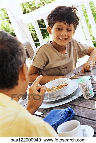 Father and son at table, close-up View Large Photo Image Stock Photo - Father and son at table, close-up . Fotosearch