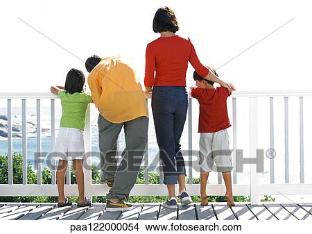Picture - Parents and children looking out to sea, rear view. Fotosearch