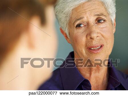 Stock Photo - Senior woman talking to younger woman, close-up, blurred foreground. Fotosearch
