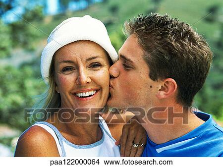 Picture - Teenage boy kissing mature woman's cheek, close-up, portrait. Fotosearch