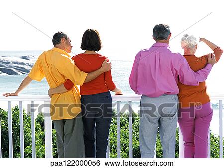 Two couples looking out to sea, rear view View Large Photo Image Stock Photograph - Two couples looking out to sea, rear view. Fotosearch