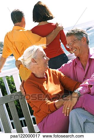 Stock Photo - Two couples, one looking out to sea. Fotosearch