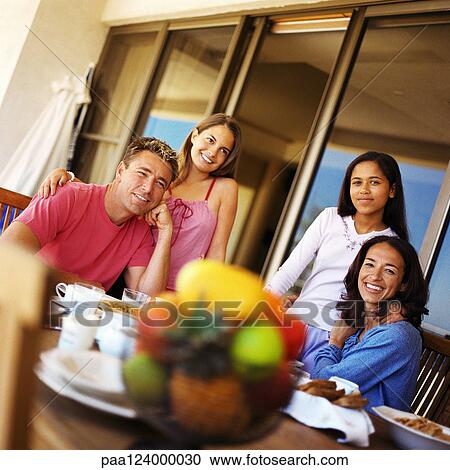Couple and daughters at table, smiling View Large Photo Image Stock Image - Couple and daughters at table, smiling. Fotosearch