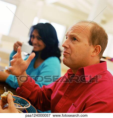 Couple sitting at table, side view View Large Photo Image Stock Photo - Couple sitting at table, side view. Fotosearch