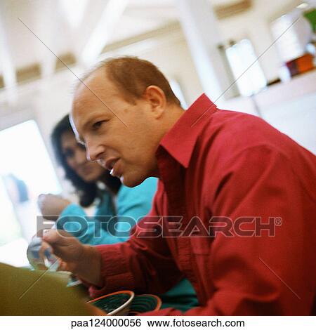 Couple sitting at table, side view View Large Photo Image Stock Photograph - Couple sitting at table, side view. Fotosearch